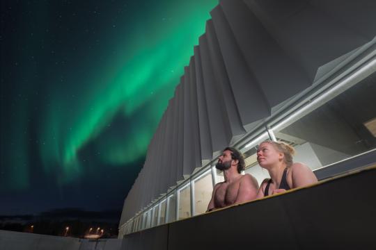 A couple enjoying the Northern Lights from the pool
