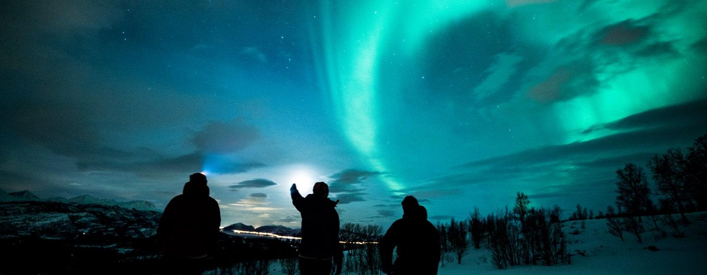Three people admiring the northern lights