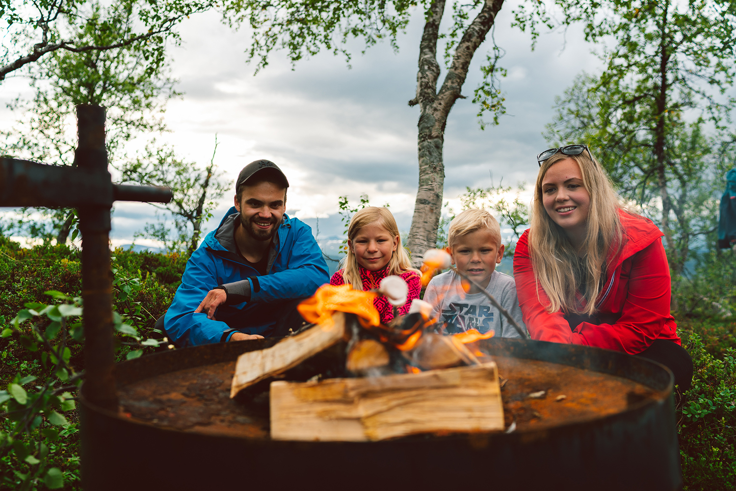 Family in front of bonfire grilling marshmallows