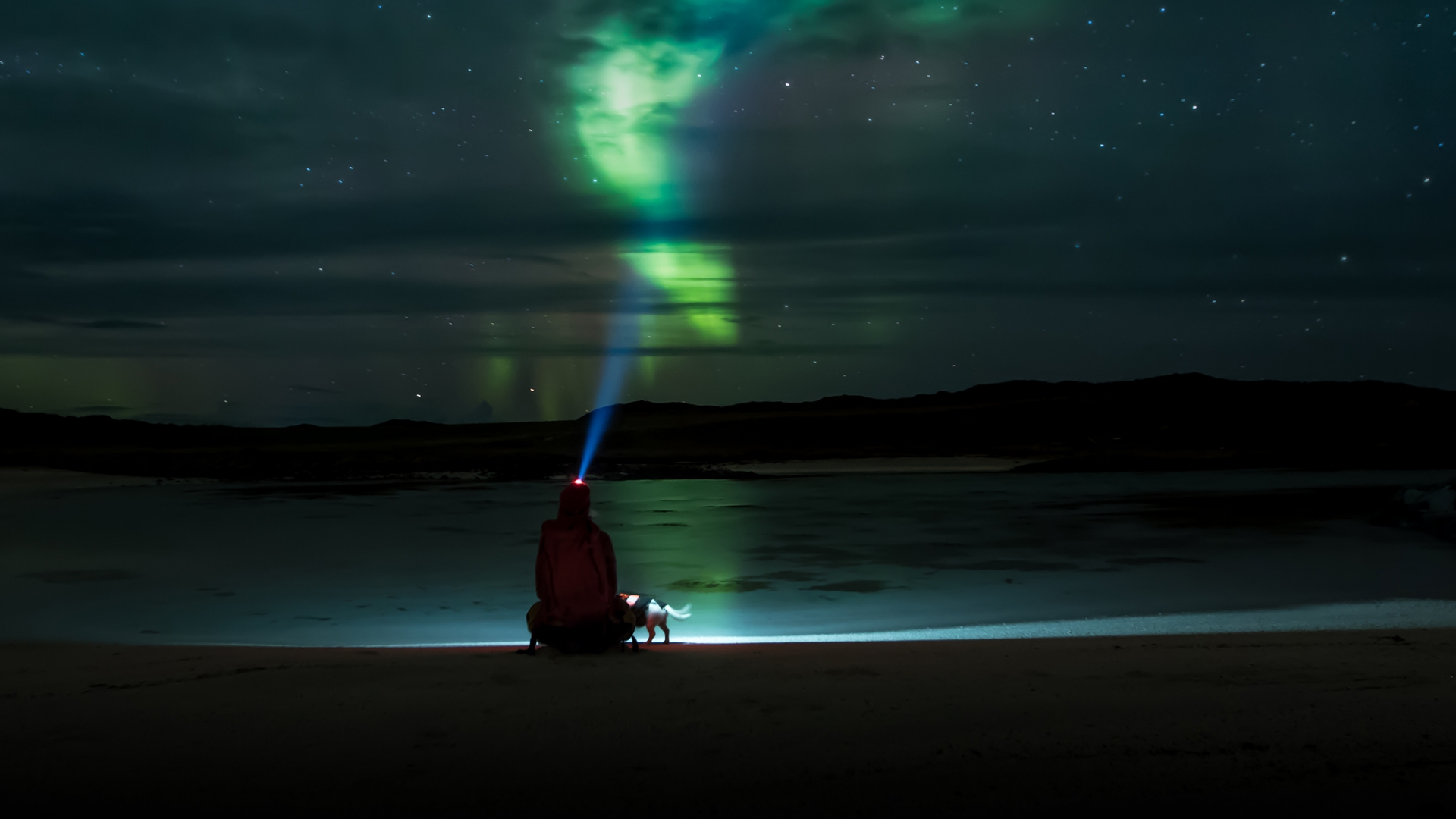 Man watching the Northern Lights from a beach