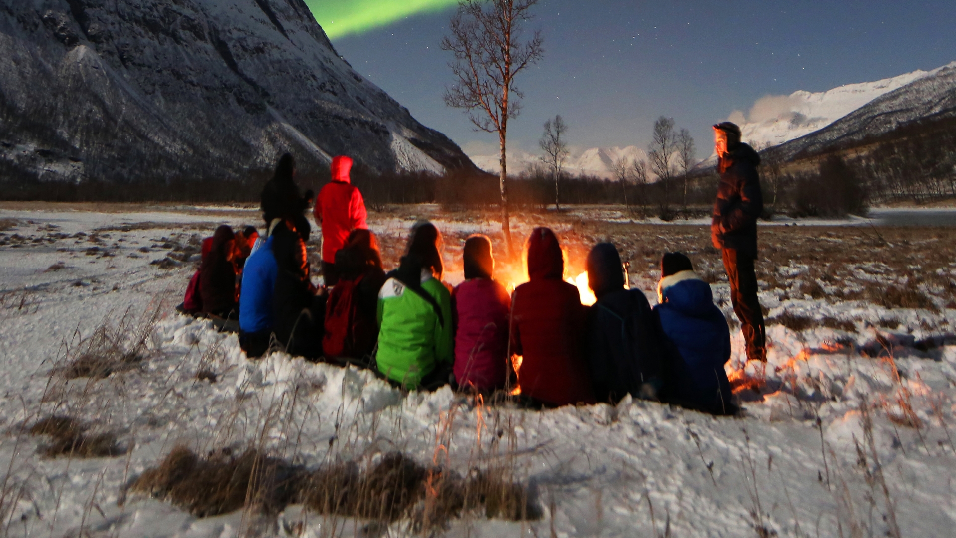 People around bonfire watching the Northern Lights