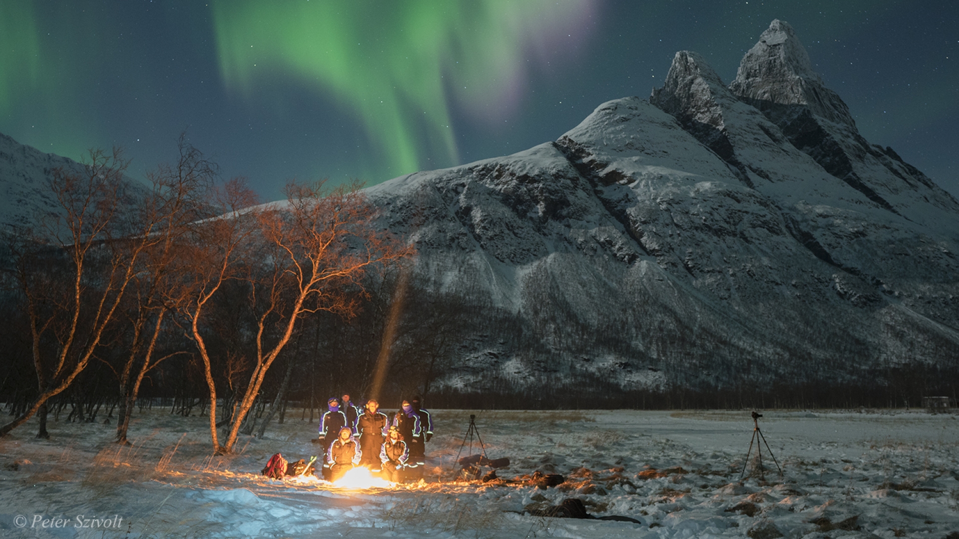 People gathered around bonfire under the Northern Lights
