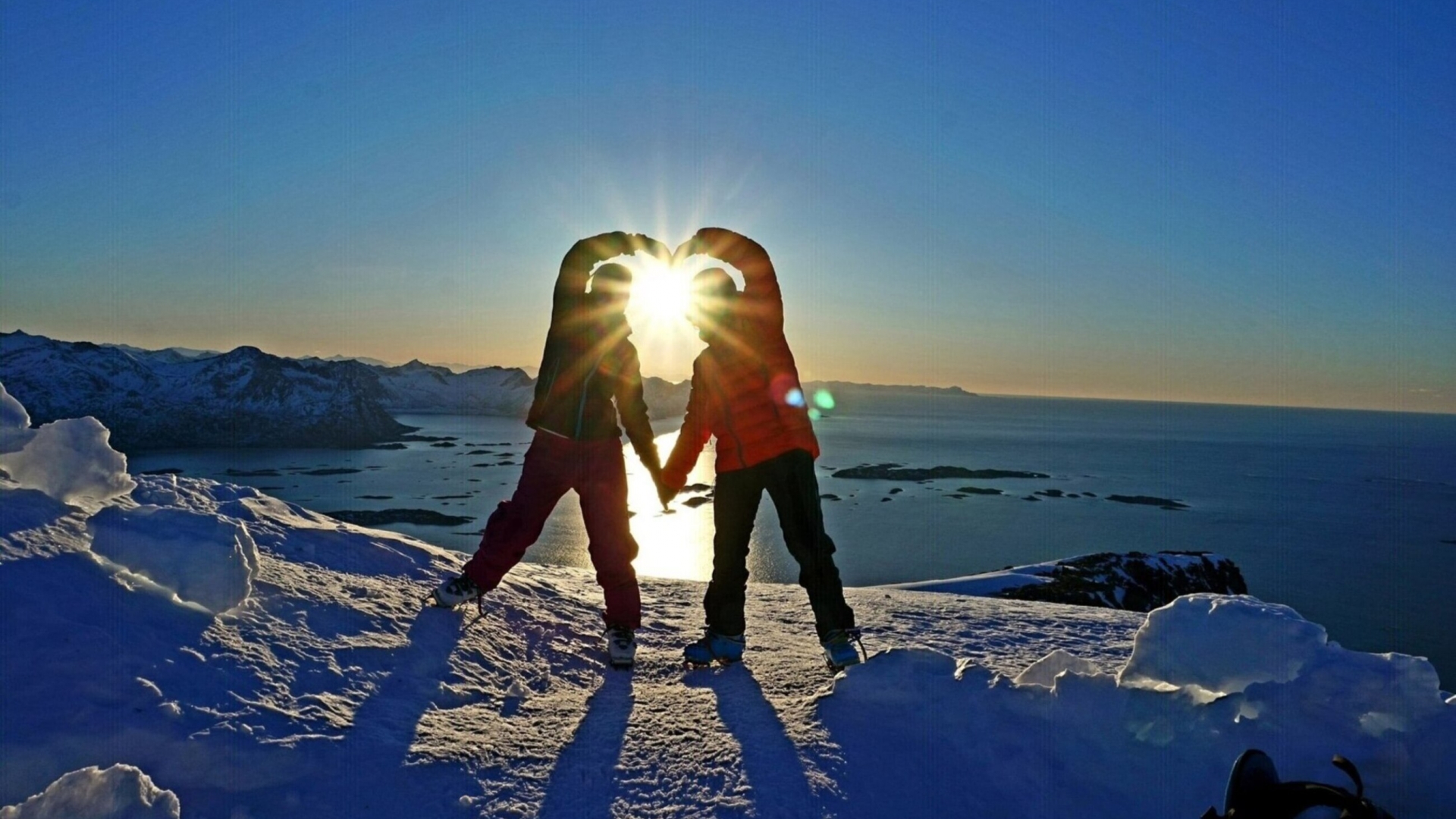 People shaping a heart with the sun in the middle in winter landscapes