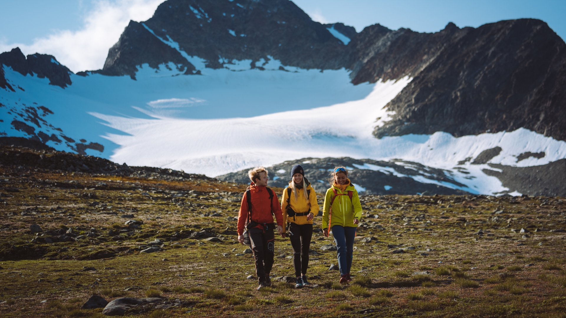 Tre venner på fjelltur i Tromsø-regionen om sommeren. Fortsatt snø på fjellet.
