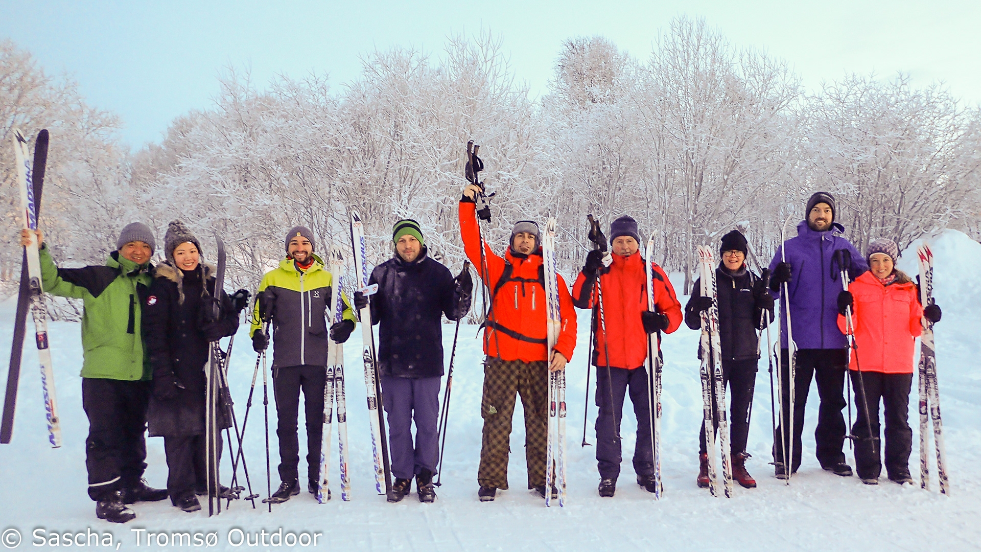 glade folk poserer foran kamera med ski