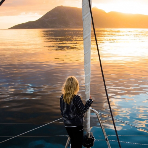 Woman standing on the edge of a boat in the Midnight Sun