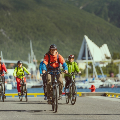 Friends bicycling on the Tromsø Harbour with the Arctic Cathedral in the background