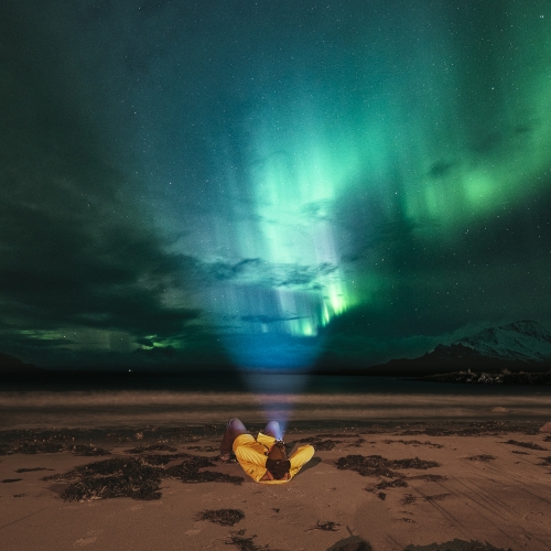 Man laying on the beach watching the Northern Lights