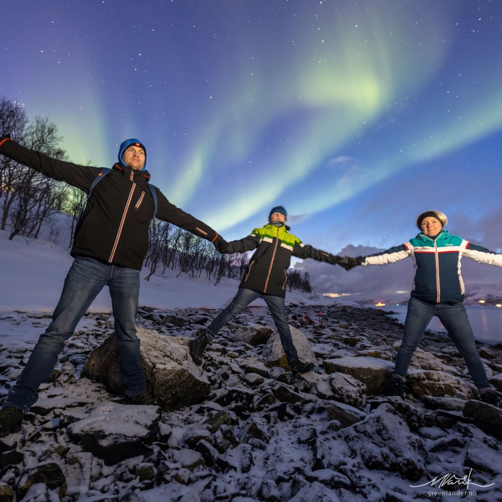 3 people holding hands under northern lights