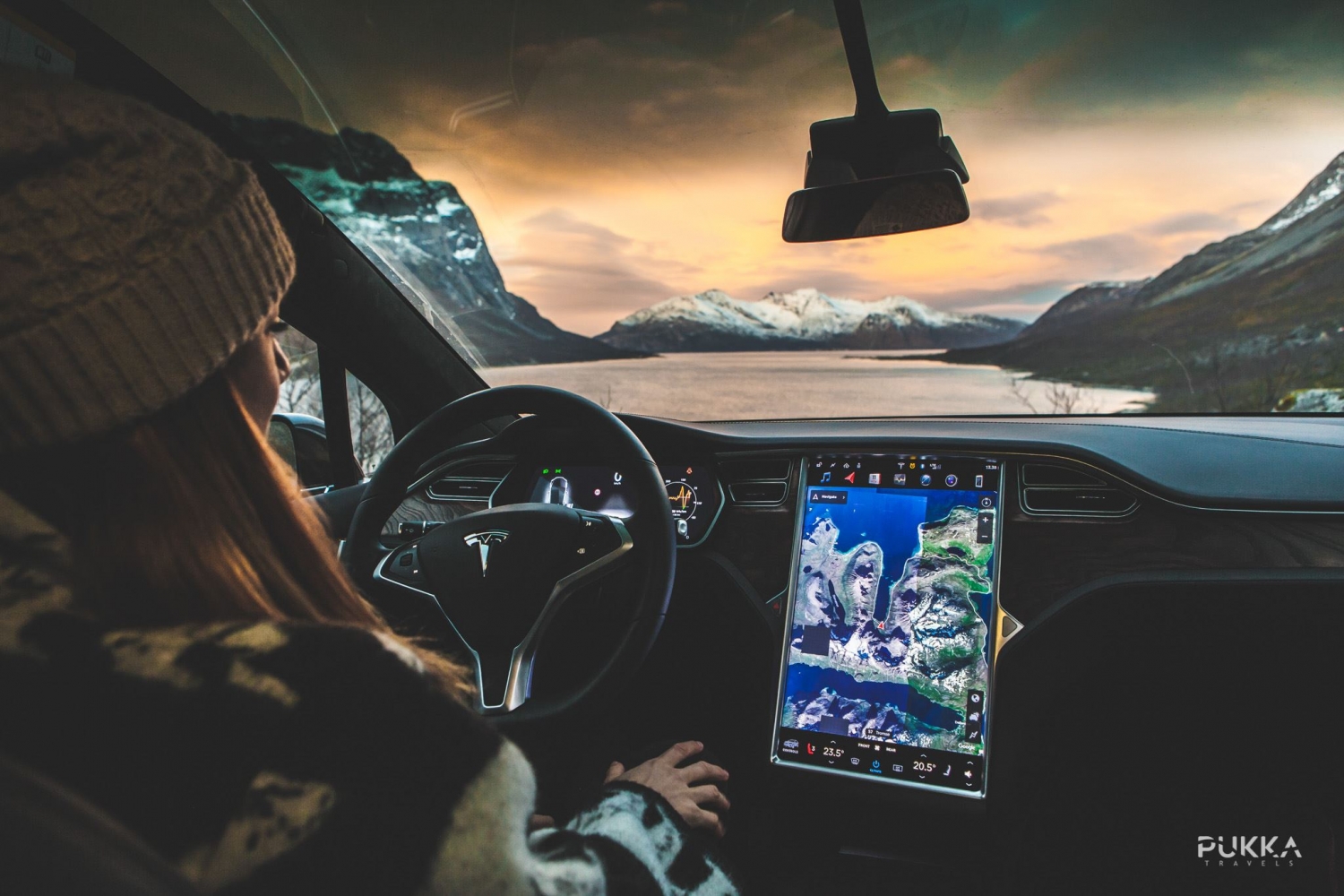 From the inside of the Tesla, colourful sky, sea and mountains in front