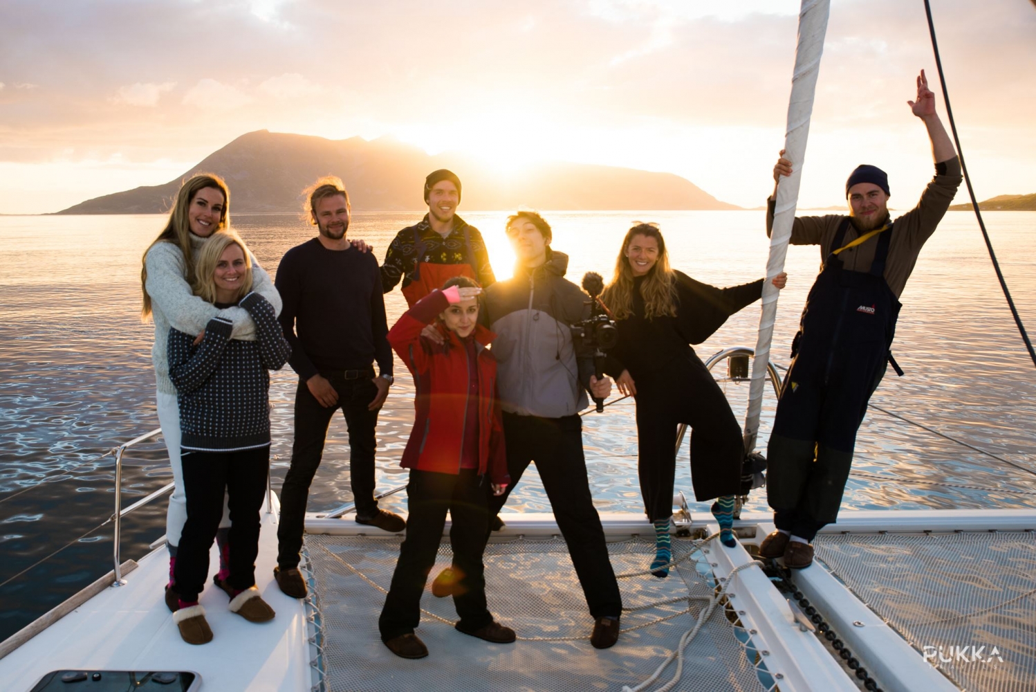 a group of  people on deck with the midnight sun in the background