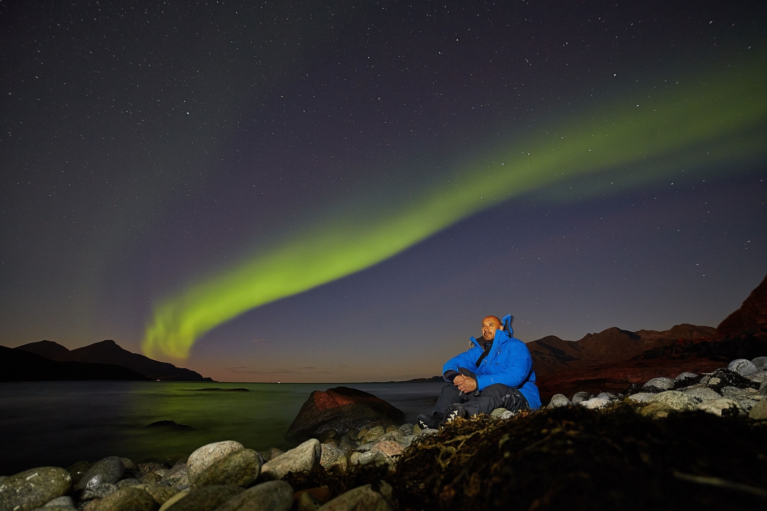 francisco is sitting by the sea with the aurora in the background