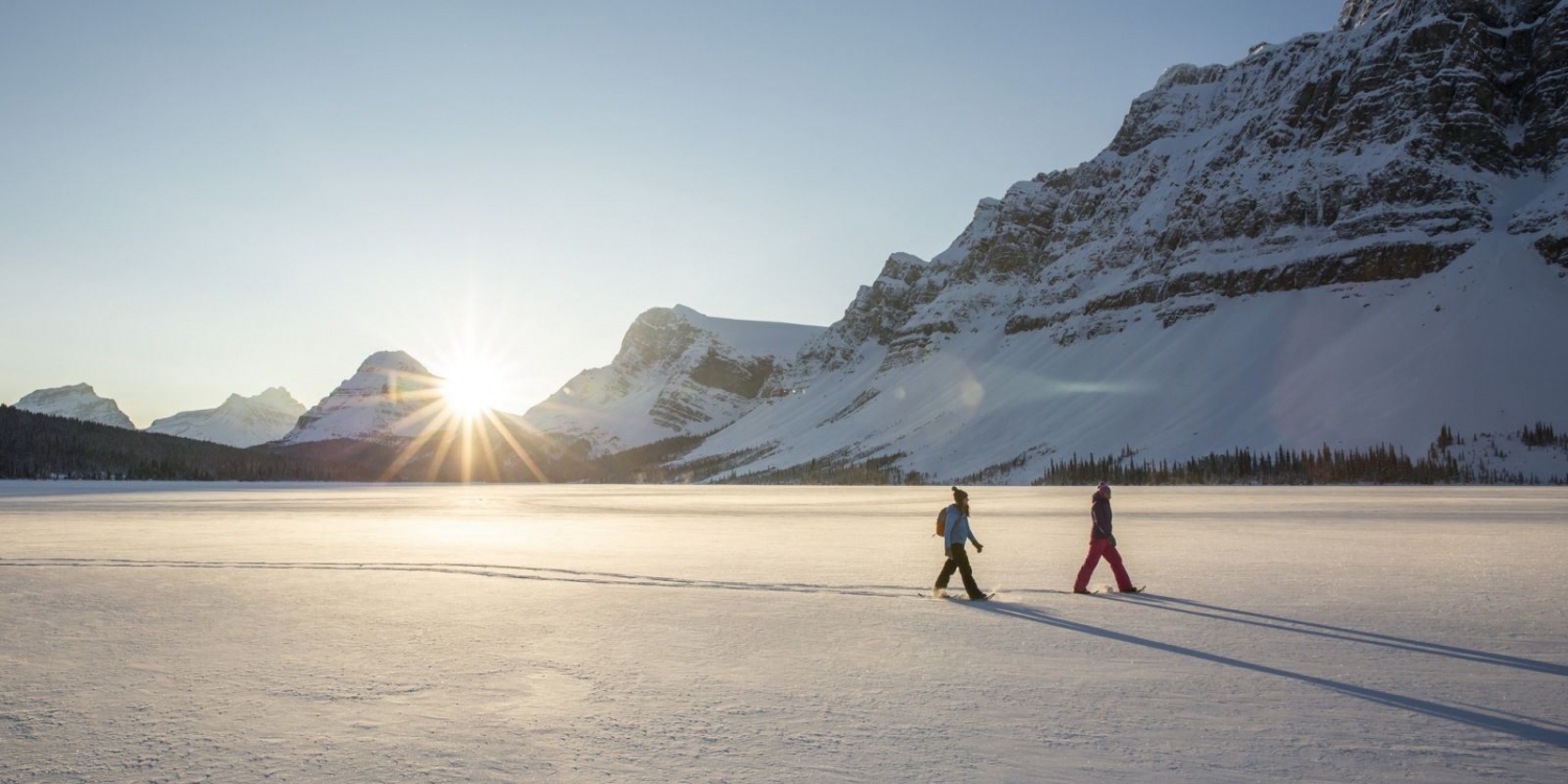 To personer går på truger på et solfylt og snødekt landskap