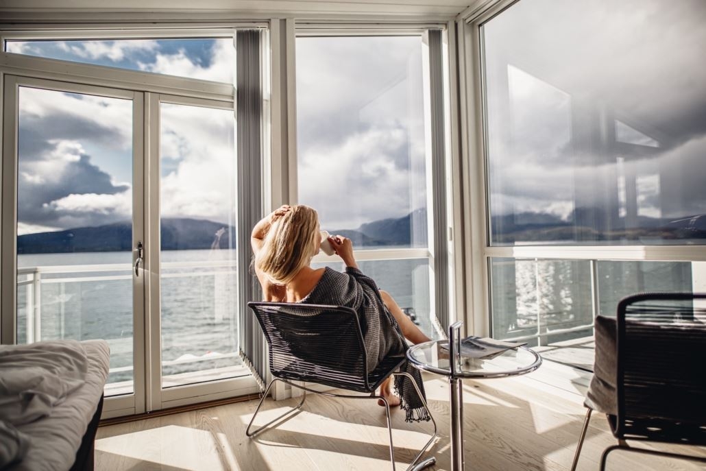 Kvinne nyter kaffe med utsikt over fjorden