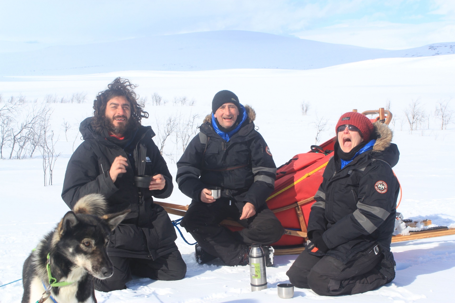 Three mushers resting next to a sled