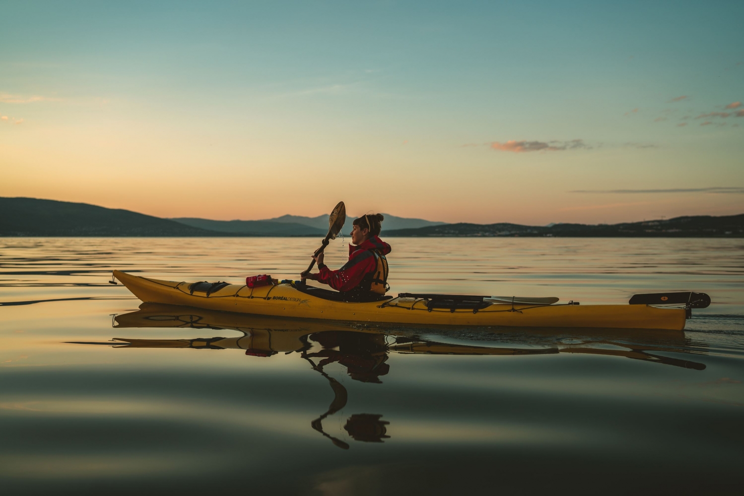 A person kayaking on a quiet ocean