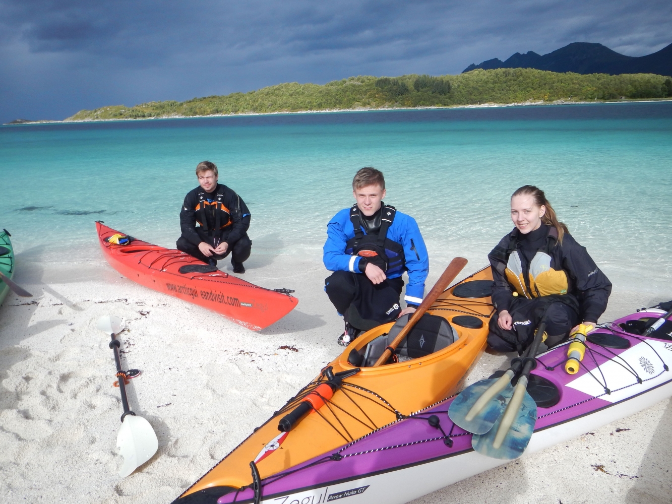 Participants preparing to go kayaking on a white sandy beach
