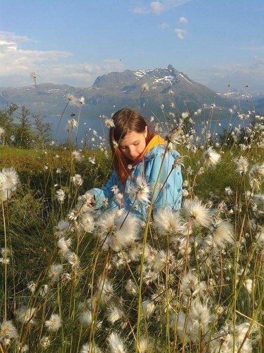 Girl sitting on the ground surrounded by cotton grass
