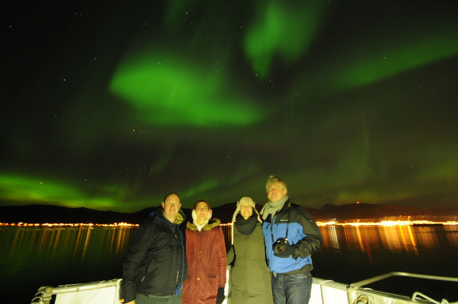 Four guests on deck with the Northern Lights in the background