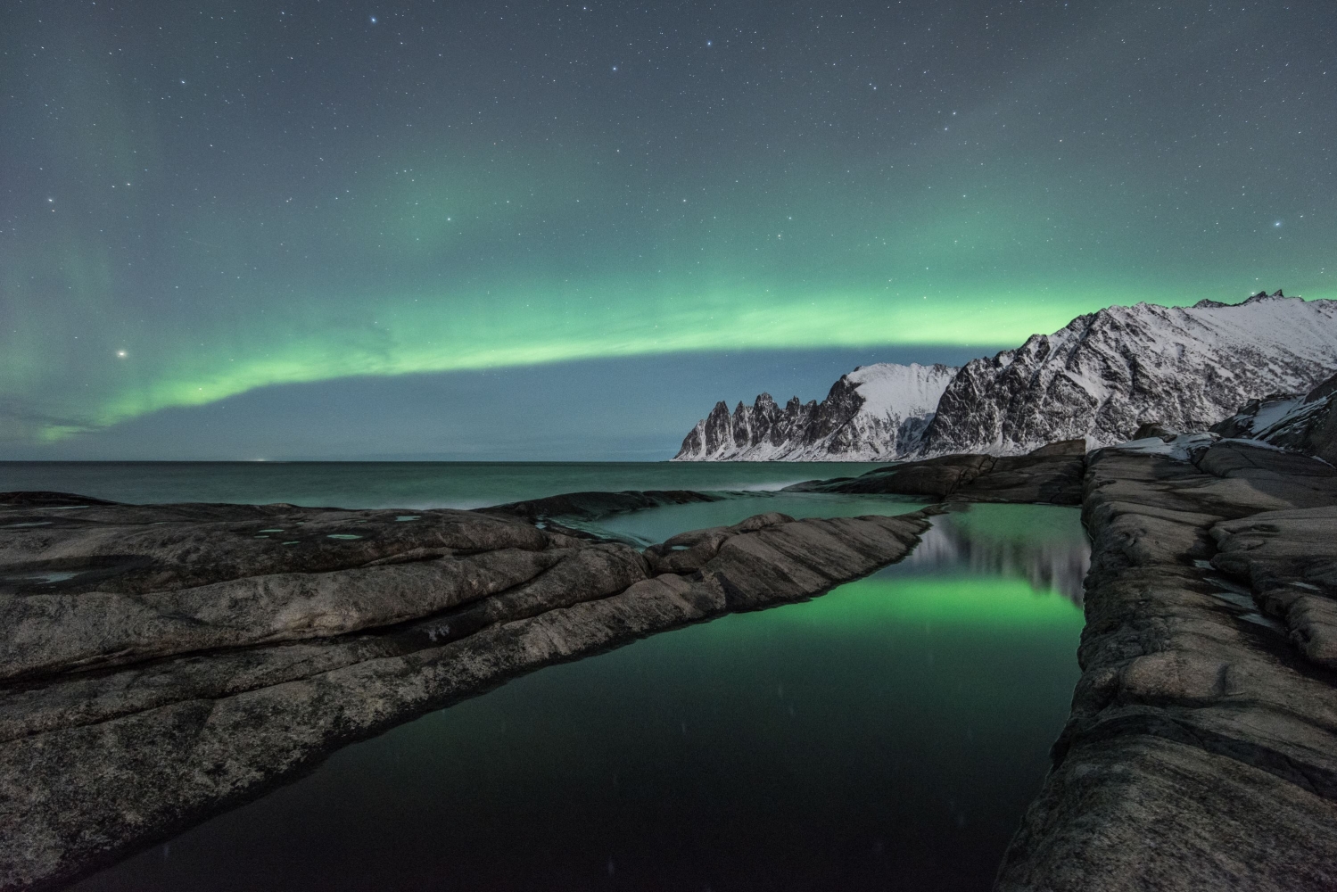Northern lights above sea and mountains