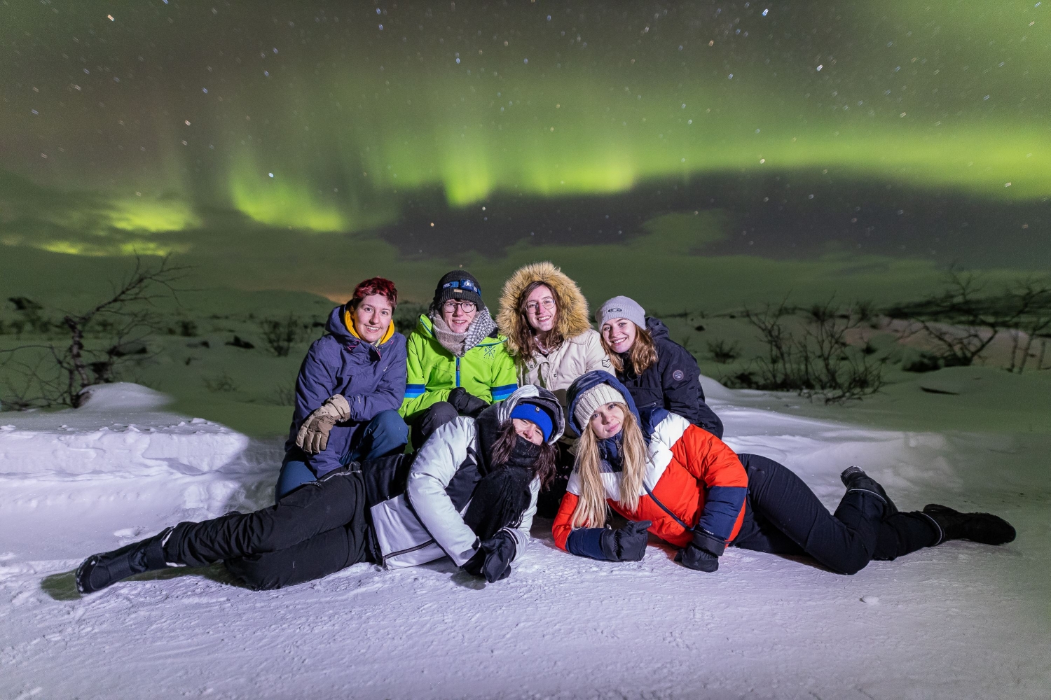group under northern lights on the snow