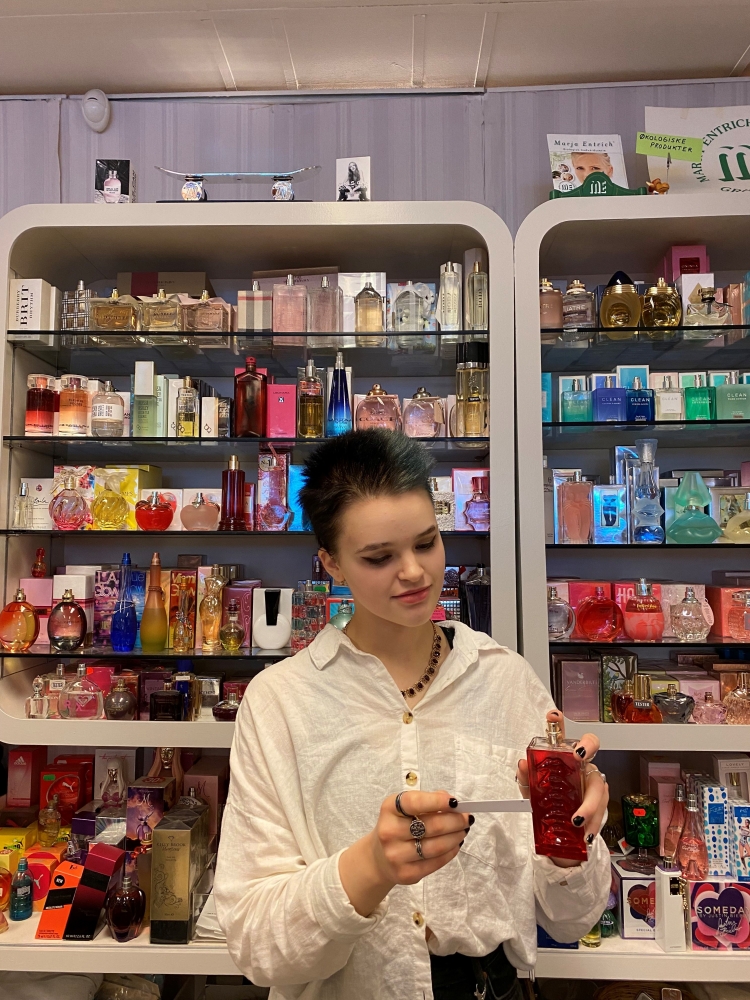 Person trying a perfume with the perfume shelf in the background