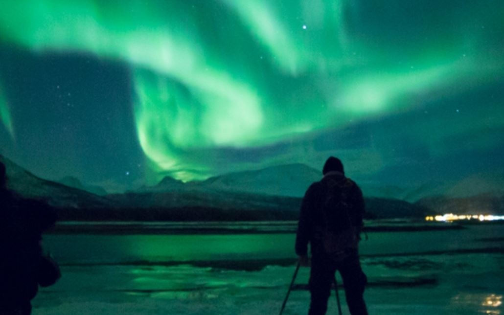 Person standing under the northern lights and taking a picture of the lights