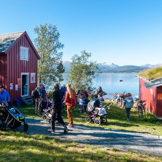 many people in the café area by the sea, old wooden house and boat house