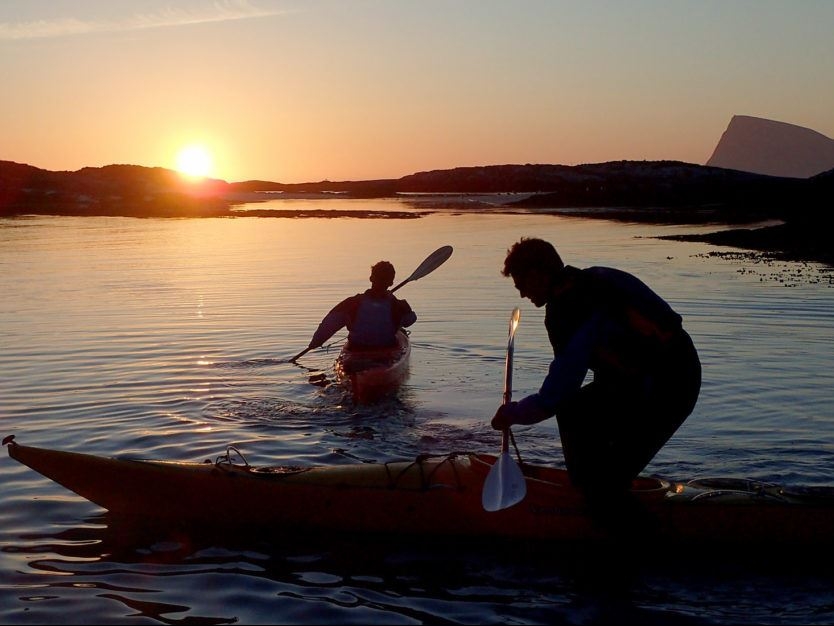two people paddling under the midnight sun