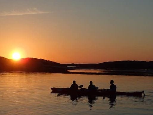three people in two kayaks looking for the midnight sun