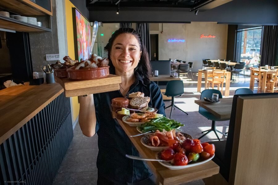Waitress smiling while holding out a tray of tapas