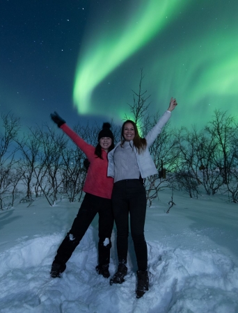 two people under a sky full of northern lights