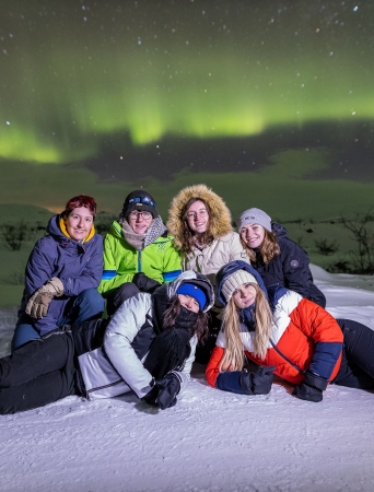 group under northern lights on the snow