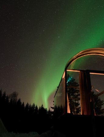 glass cabin with northern lights above