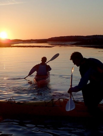 two people paddling under the midnight sun