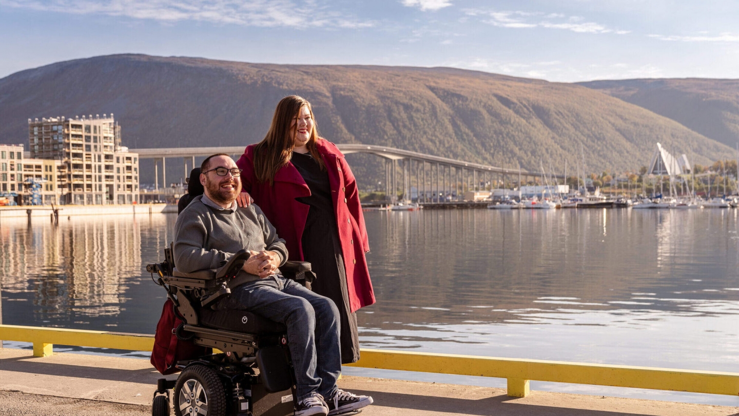 To personer, en i rullestol, som er på sightseeing i havnen i Tromsø