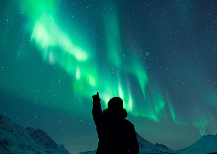 Person pointing towards the northern lights in the Tromsø region