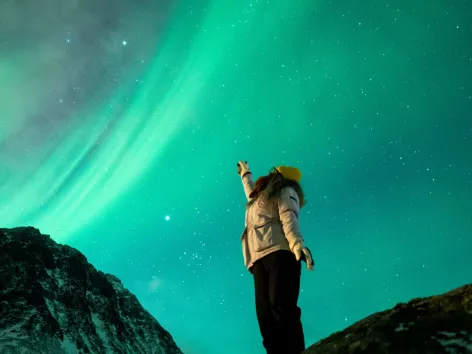 A girl pointing towards the skies full of northern lights