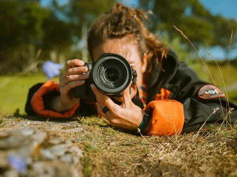 Woman laying on the ground to take a photo with a photo camera