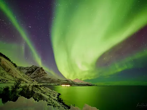 Nordlys over hav og fjell i Tromsøregionen om vinteren