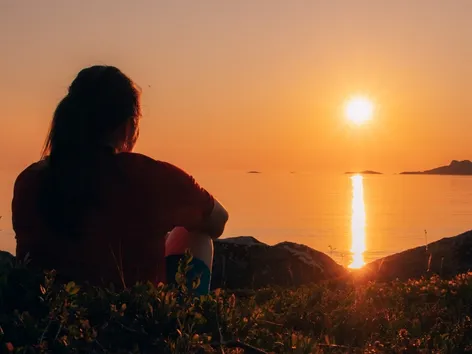 Woman sitting in nature and enjoying the midnight sun in the Tromsø region.