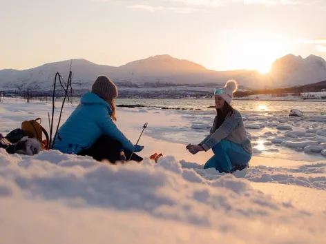 Friends enjoying the outdoors in winter landscape by the sea in the Tromso region