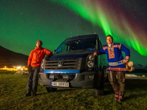 Gjester poserer foran minibuss og nordlyset