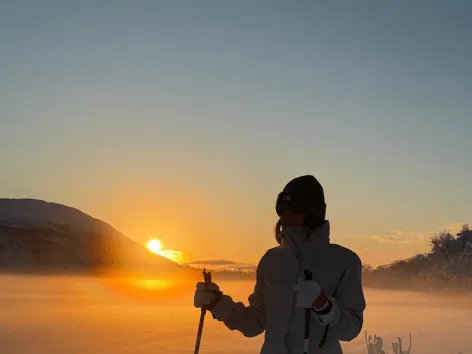 Gjest går på ski med sola i horisonten