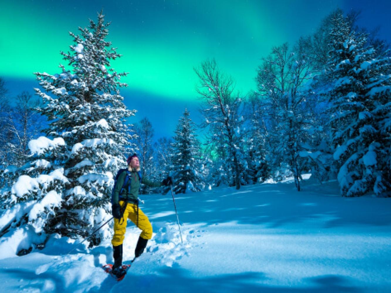 Lady enjoying the northern lights with snowshoes