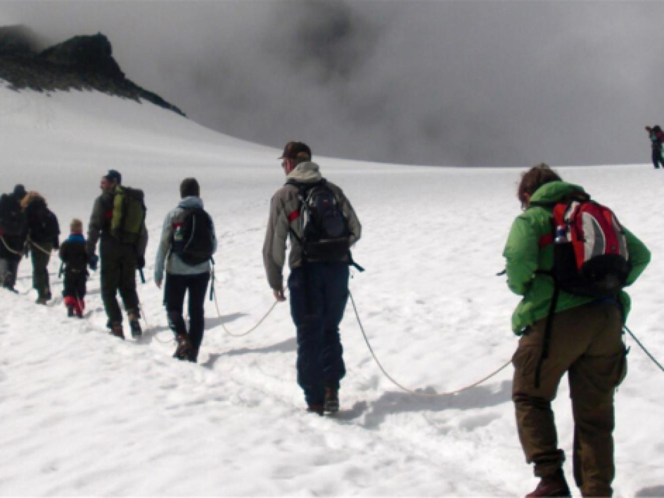 En gruppe mennesker går opp en snødekt fjellside på en guida tur.