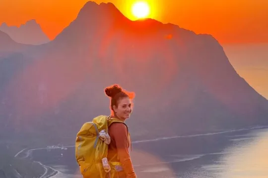 Gjest ser på midnattsola over fjellet