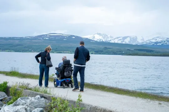 Tre personer på tur med snødekte fjell i bakgrunnen
