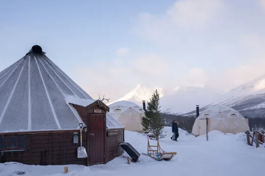 A lavvu and several tents in the snow in an Arctic setting