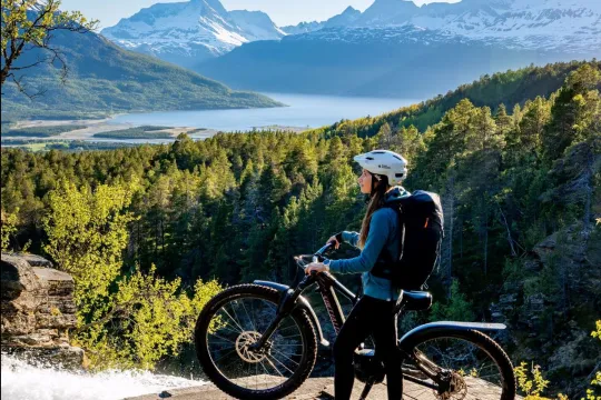 Person med sykkel ser på utsikten over fjord og fjell